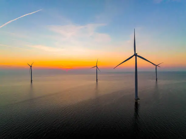 Photo of Wind turbines in an offshore wind park producing electricity during sunset.