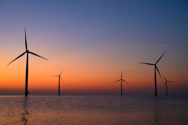 istock Wind turbines in an offshore wind park producing electricity during sunset. 1385115328
