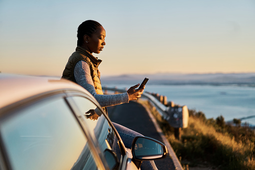 istock Shot of a young woman using a smartphone on a road trip 1385115962