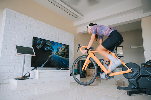 Asian Chinese woman cycling with stationary bicycle trainer at home