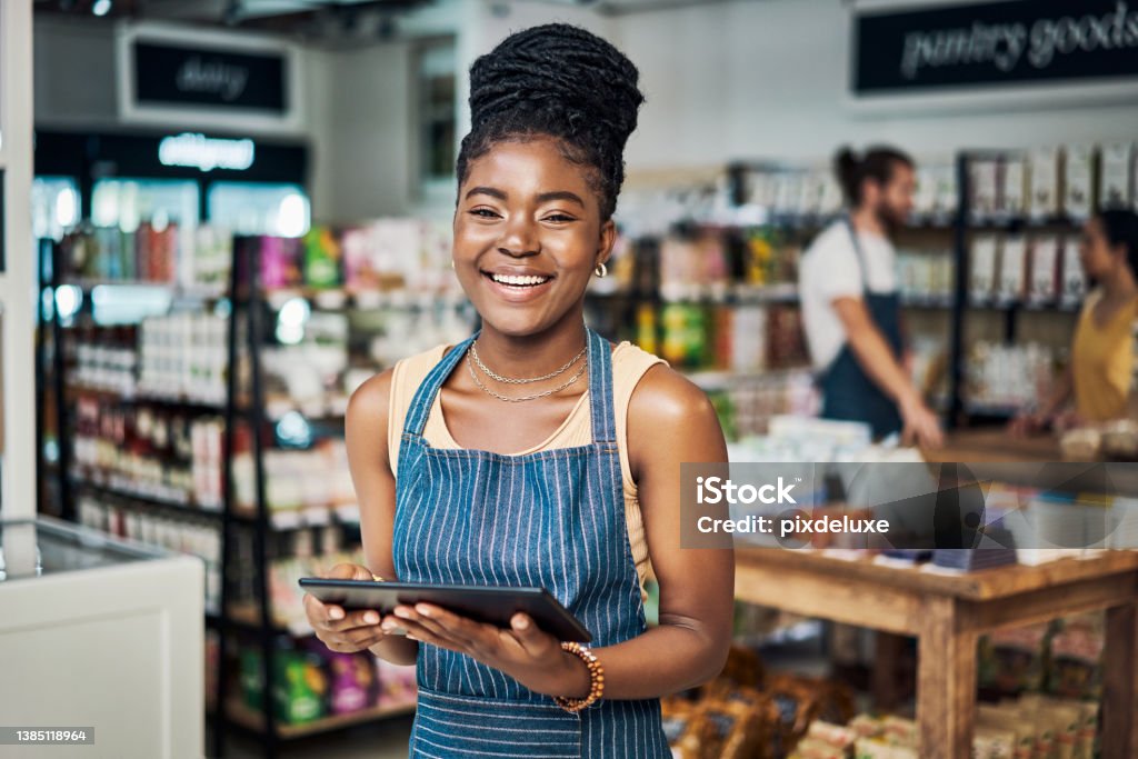 Shot of a young woman using a digital tablet while working in an organic store Come in, take a look around Small Business Stock Photo