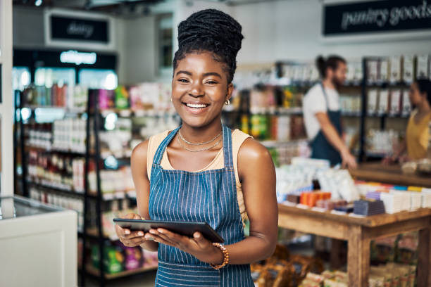 Shot of a young woman using a digital tablet while working in an organic store Come in, take a look around retail occupation stock pictures, royalty-free photos & images
