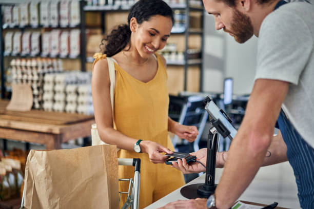 scatto di una giovane donna che paga con una carta di credito in un negozio biologico - credit card shopping retail buying foto e immagini stock