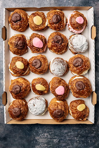Fastelavnsbolle or Fastelavn cakes are a Danish delicacy made and eaten in great quantities in many parts of Scandinavia  in the period up to the beginning of Lent. Made from puff pastry and filled with cream and or jam and topped with a variety of different flavours, fruits, chocolate and icing.  Colour, vertical format with some copy space.