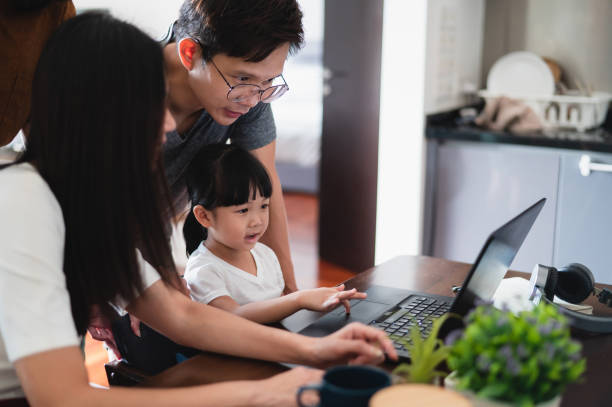 istock Asian parents assists their daughter with E-learning video call at home 1385120736