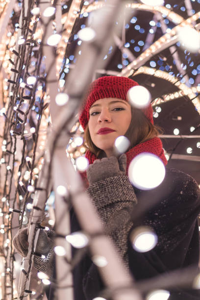 istock Red hat girl standing inside  Christmas tree lights at night 1385121068