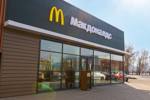 Bila Tserkva, Ukraine - January 16, 2022: Exterior view of McDonald's fast food restaurant with street tables from the side on a city street and people on the background.