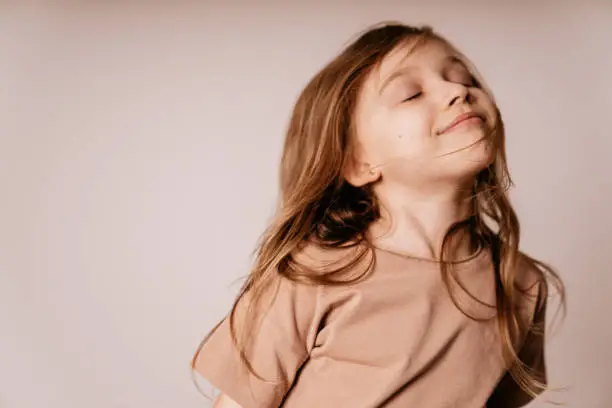 Photo of Authentic portrait of a smiling small girl with long brown hair.