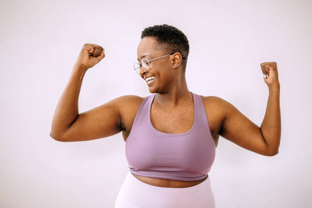 Woman strength, determination, healthy lifestyle Young beautiful plus size woman flexing muscles body confidence stock pictures, royalty-free photos & images