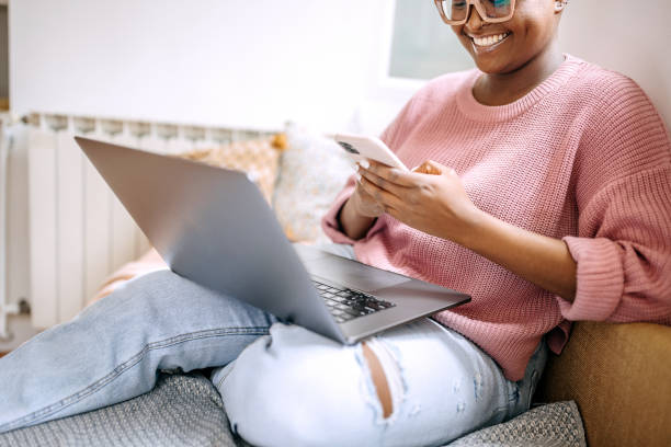 istock Young woman using mobile phone and laptop at home 1385126662