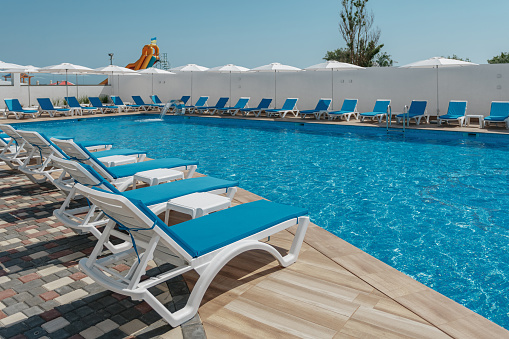 view of the pool with blue water and sun loungers. High quality photo