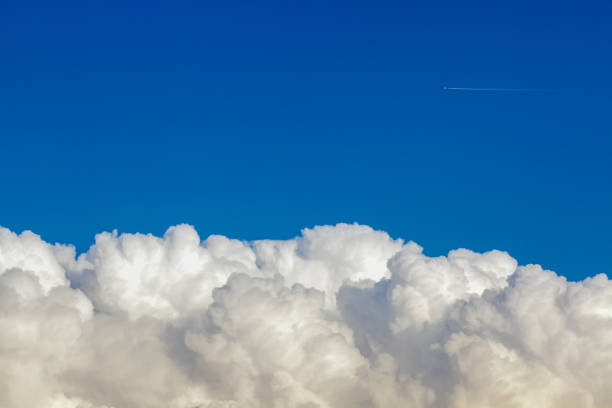 istock Plane flying over the clouds in a blue sky 1385127085