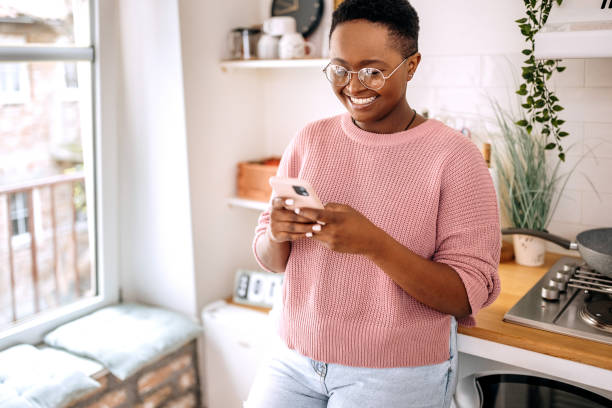 istock Happy woman using mobile phone in her apartment 1385127144