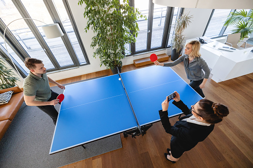 Top view of two colleagues playing table tennis in office