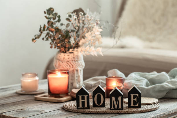 Cozy home background with decorative word home and candles on blurred background.
