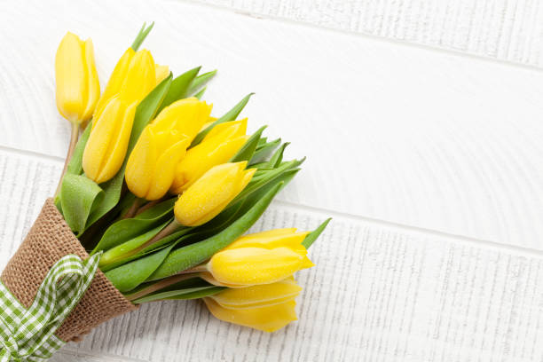 Yellow tulip flowers bouquet on wooden table. Top view flat lay with copy space