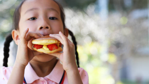istock a girl eating strawberry confection. 1385152459