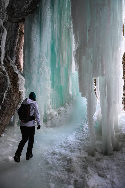 istock Female hiker relaxes under frozen waterfall 1385155804