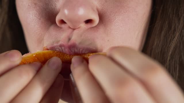 Woman eating red orange slice close up