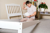 istock A puzzled, tired father cobbles the baby bed, wipes the sweat off his face. 1385157235