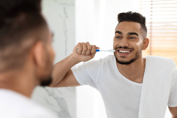 istock Handsome Millennial Arab Guy Brushing His Teeth With Toothbrush In Bathroom 1385157341