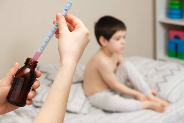The pediatrician or mother types in a measuring syringe the medicine for cough or temperature syrup for the child The pediatrician or mother types in a measuring syringe the medicine for cough or temperature syrup for the child. child liquid medicine stock pictures, royalty-free photos & images