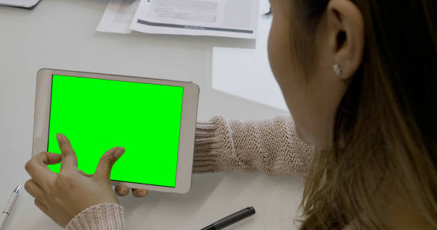 istock Young woman using a tablet with a green screen 1385162940