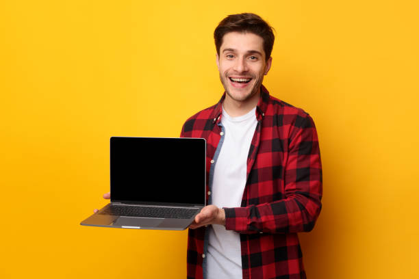 istock Happy young man showing black empty laptop screen 1385163015