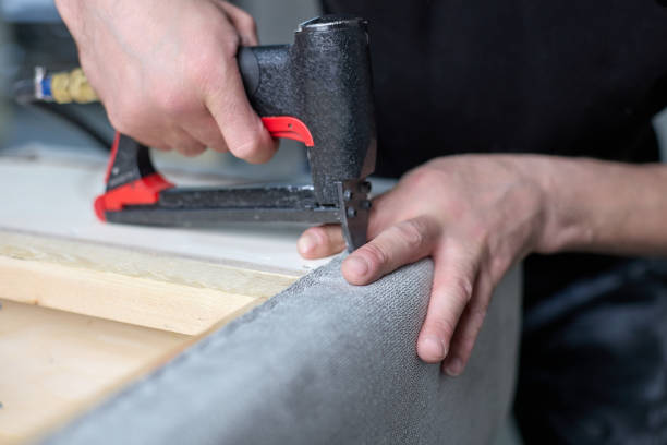 der arbeiter fixiert den stoff mit einem pneumatischen hefter in der werkshalle. - polstermöbel stock-fotos und bilder