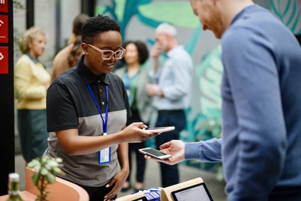 istock Conference Staff Member scan a QR code from attendee upon arrival to check-in site 1385168398
