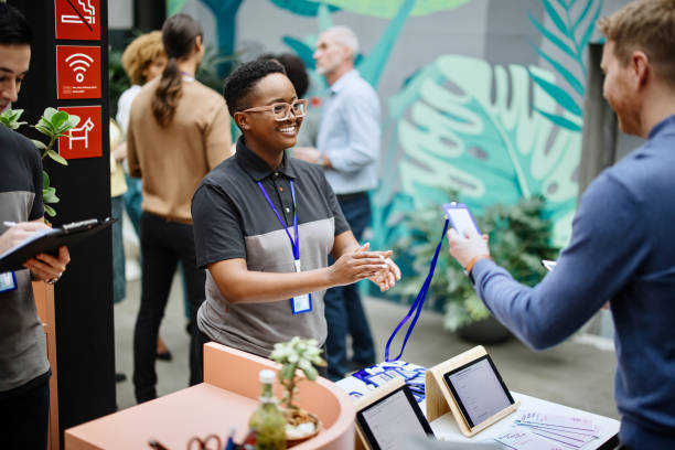 istock Conference Staff Member handing out accreditation to attendee 1385168438