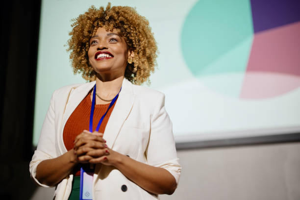 close up of a visionary female speaker smiling and looking at the audience - presentatie stockfoto's en -beelden