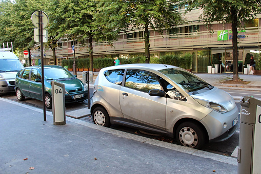 Power supply connect to electric vehicle for battery charging. Charging technology industry, which are the futuristic of the automobile. EV Fuel Plug in Hybrid Car, car for rent on a street in Paris. September 2013.