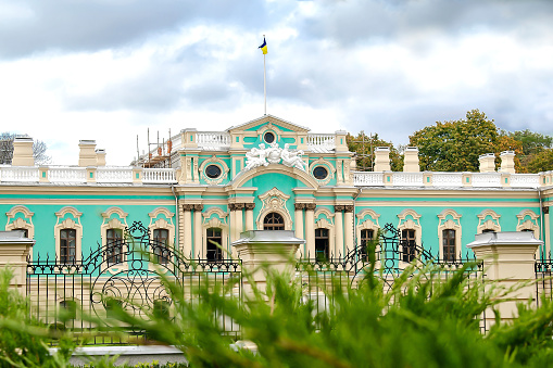 Luxury national Mariyinsky Palace building in Kiev is official ceremonial seat of the Ukrainian president with green ornamental bushes in foreground.