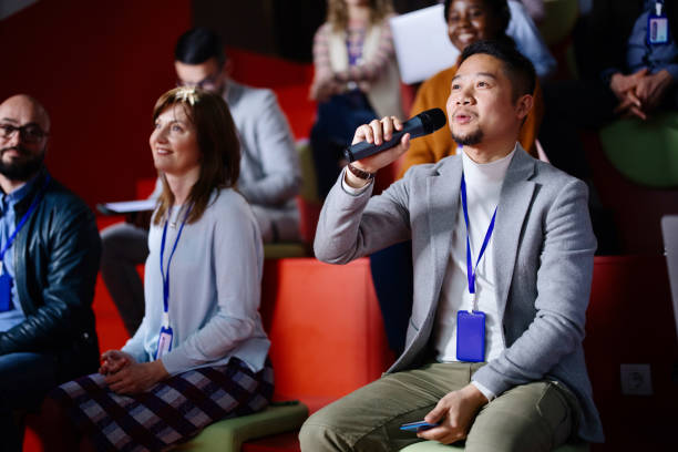istock A confident Asian business man in the audience asking a question into a microphone at a seminar. 1385170323