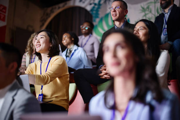 istock Multi-ethnic audience sitting in an amphitheater while listening to presentation at conference 1385170481