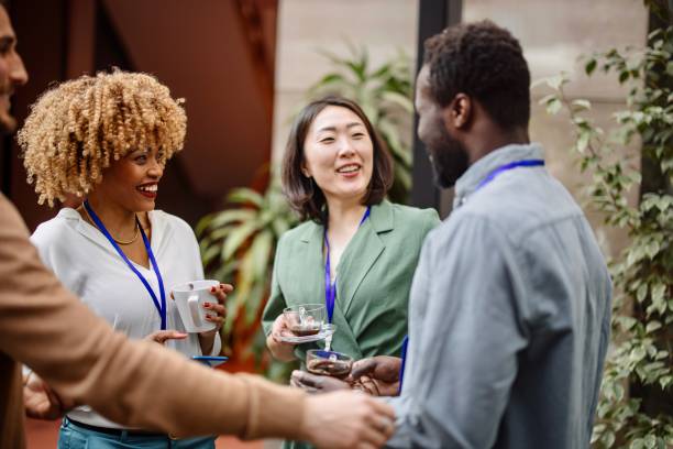 Multiethnic business people talk during a coffee break Business people communicating at convention center smart casual stock pictures, royalty-free photos & images