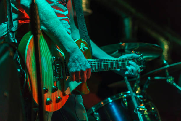 der gitarrist spielt auf der gitarre in einem dunklen raum. hände eines gitarristen, der gitarre spielt. zurückhaltend - akkord stock-fotos und bilder