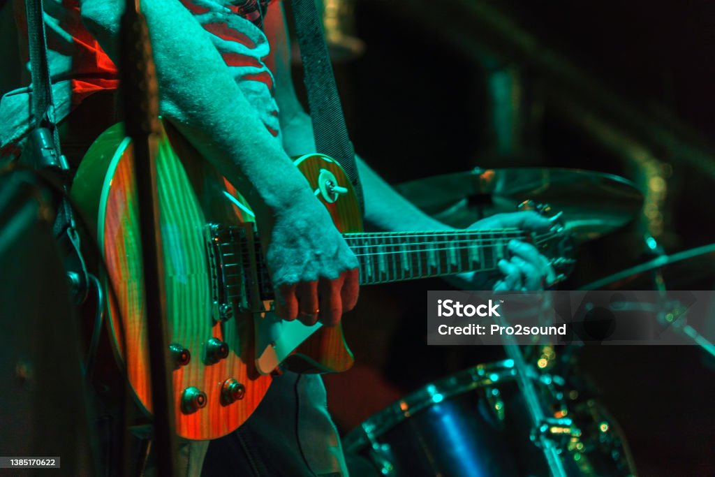 The guitarist plays on guitar in a dark room. Hands of a Guitar player playing the guitar. Low key Rock Music Stock Photo