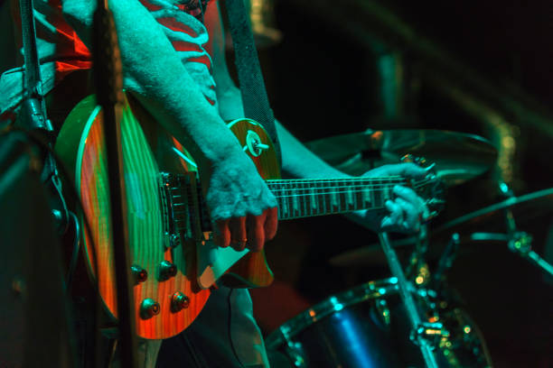 the guitarist plays on guitar in a dark room. hands of a guitar player playing the guitar. low key - concert imagens e fotografias de stock