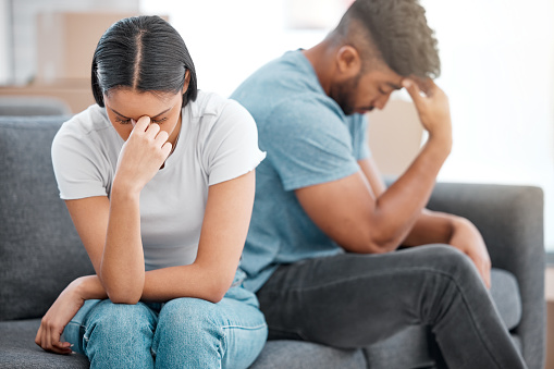 Shot of a young couple sitting on the sofa at home and ignoring each other after a fight