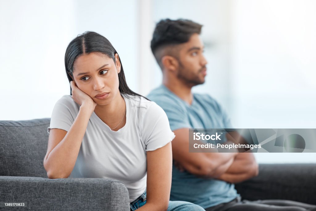 Shot of a young couple sitting on the sofa at home and ignoring each other after a fight I'm not happy at all Couple - Relationship Stock Photo