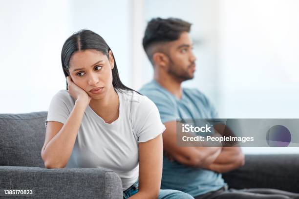 Shot Of A Young Couple Sitting On The Sofa At Home And Ignoring Each Other After A Fight Stock Photo - Download Image Now