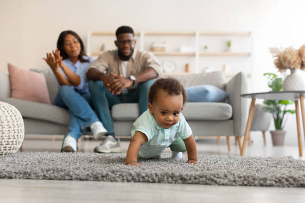 istock Cute baby toddler walking in living room making first steps 1385175232