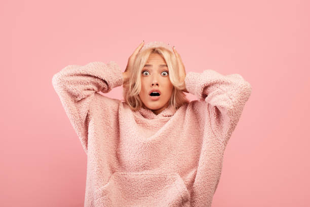 Omg. Young emotional lady holding her head in shock, cannot believe amazing offer or sale, opening her mouth in surprise Omg. Young emotional lady holding her head in shock over pink studio background. Amazed woman cannot believe amazing offer or sale, opening her mouth in surprise wtf stock pictures, royalty-free photos & images