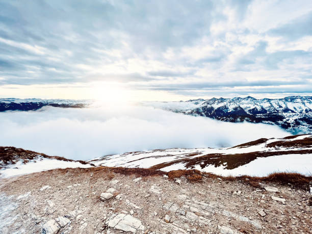 Sunny snowy landscape over the clouds with sunlight