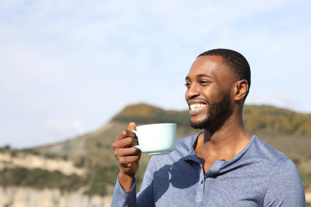 istock Happy man with black skin laughing and drinking coffee 1385178215