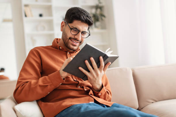 istock Young Arab man in glasses reading book 1385180829