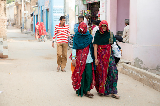 Alsisar, Indien - April 7, 2020: Street scene in in Alsisar, Rajasthan. People walking on the street, in the foreground are seen two indian women in traditional clothing.