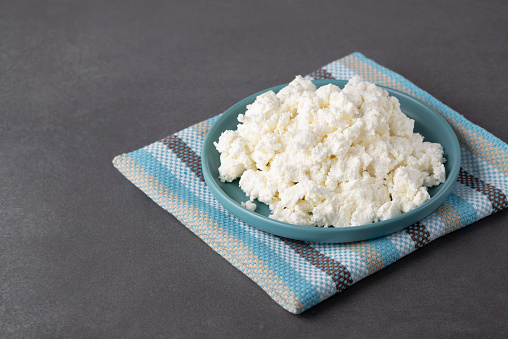 Bowl with fresh cottage cheese on table. Space for text.